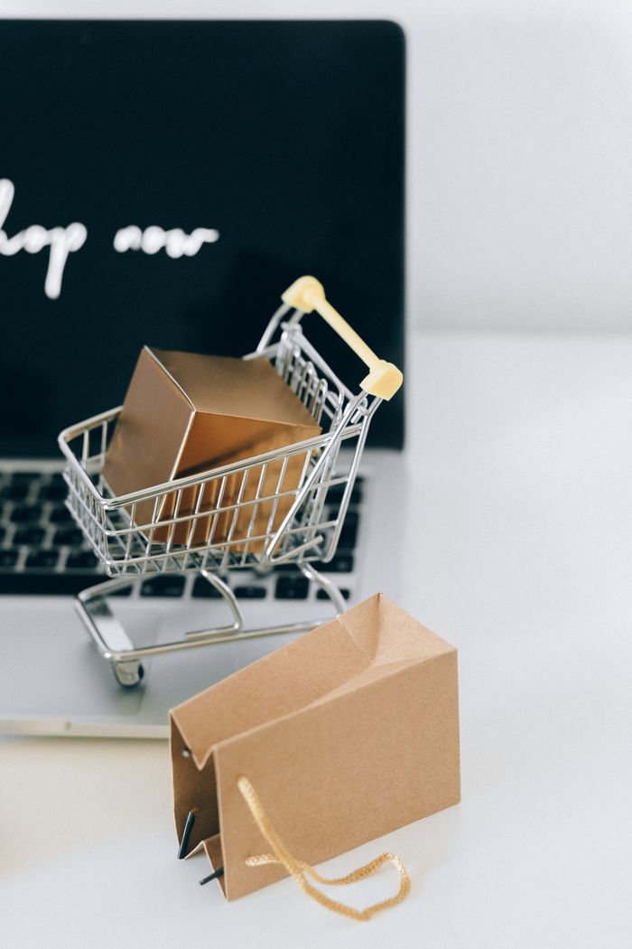 The Art of Drawing Readers In: Your attractive post title goes here A miniature shopping cart with a parcel on a laptop symbolizes online shopping and e-commerce.
